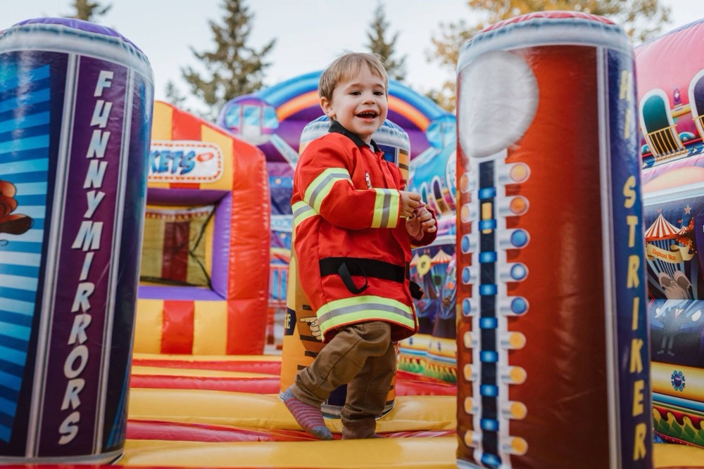 A child beaming on the bounce house at a Bright Skies event